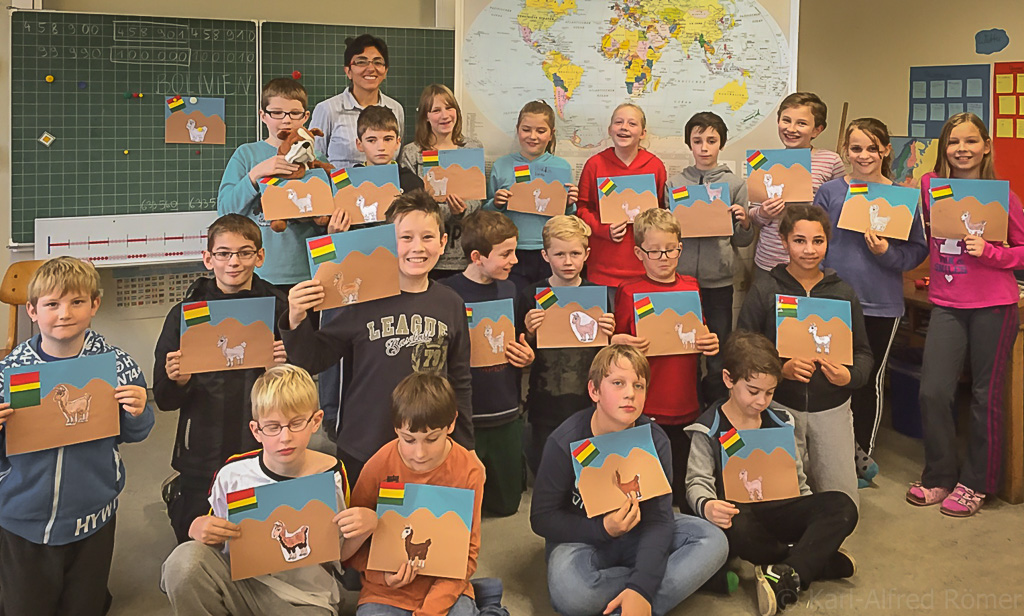 Klassenfoto mit bolivianischer Gastlehrerin vor dem Schultafel. 