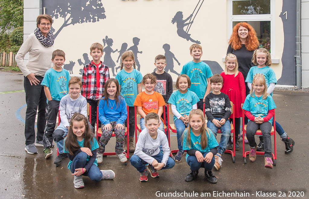 Grafik: EinzelfoGemeinsames Klassenfoto aller SchÃ¼ler der Klasse 2a und mit Lehrerinnen Frau Neuber und Frau Kaivers. Im Hintergrund die bemalte Front der Grundschule.