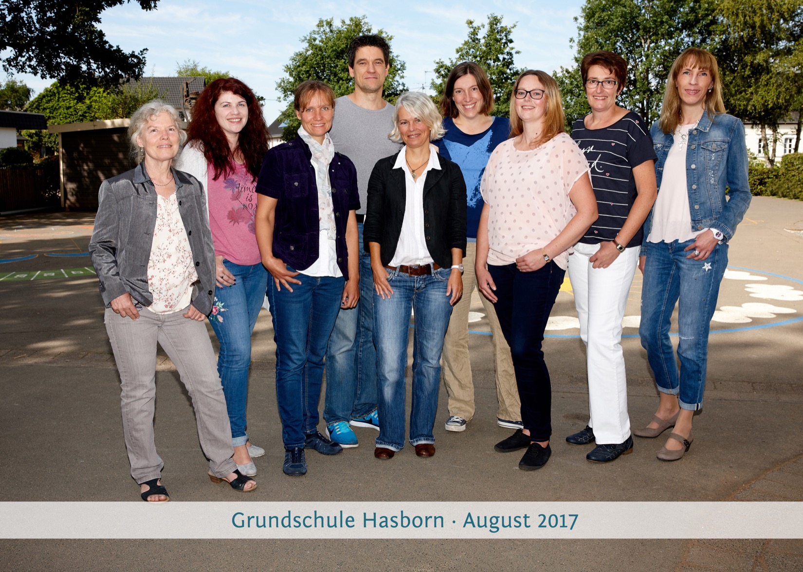 Gruppenfoto der 7 aktuellen Lehrer auf den sonnigen Schulhof