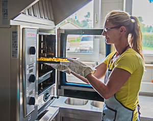 Köchin nimmt Pommes aus Backofen