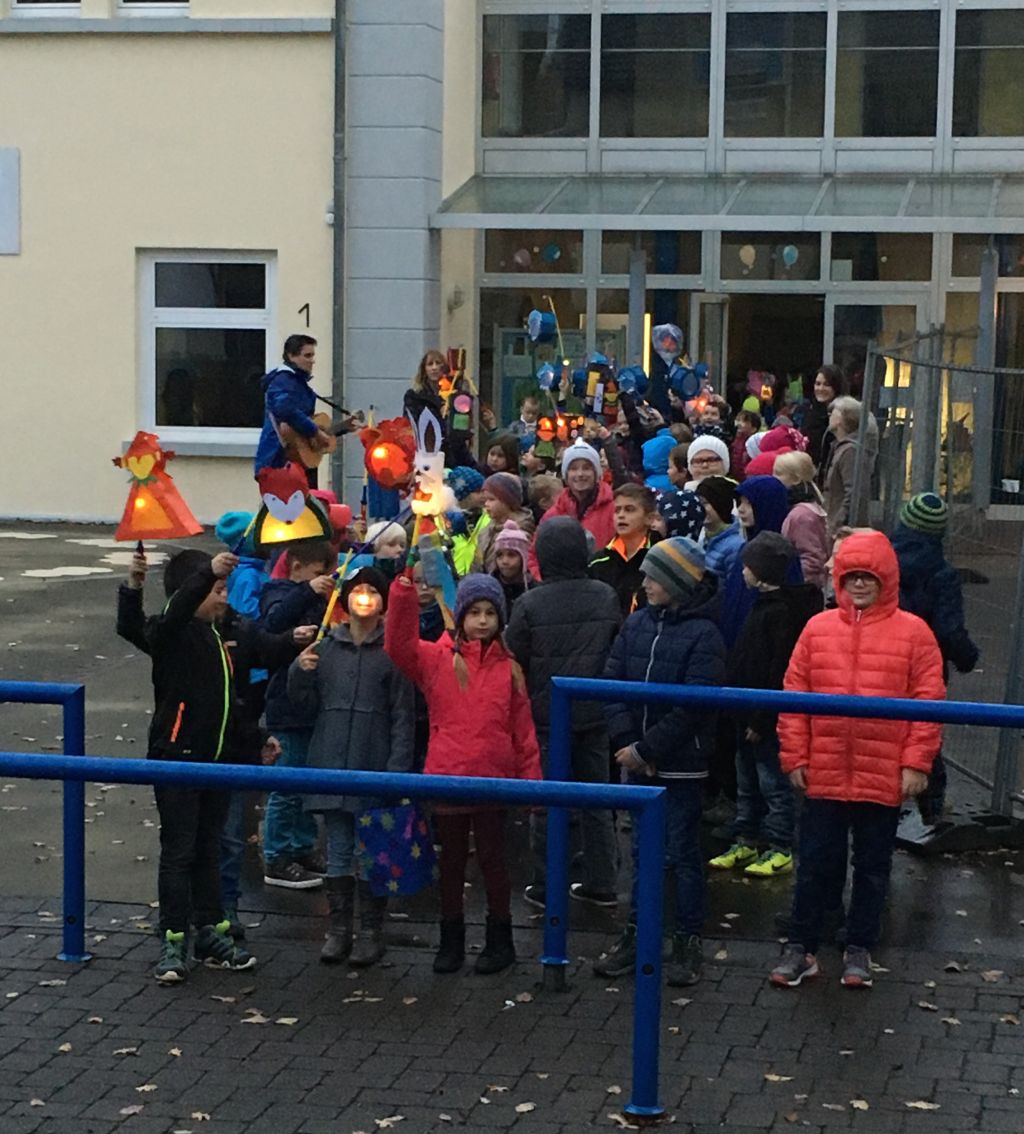 Alle Schulkinder mit ihren Laternen noch in der MorgendÃ¤mmerung am Startpunkt vor dem Schuleingang